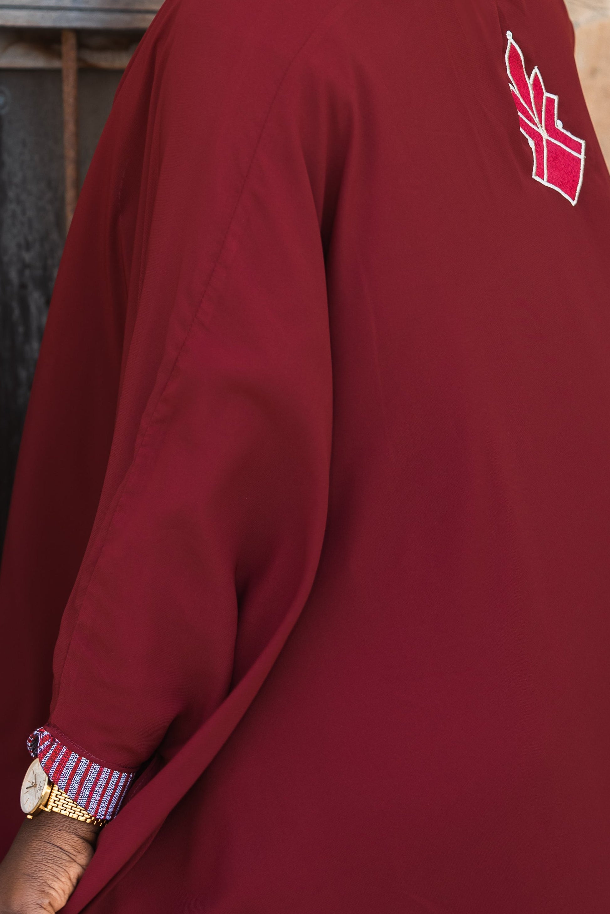 Woman in a burgundy dress with a red heart design, standing against a textured wall.