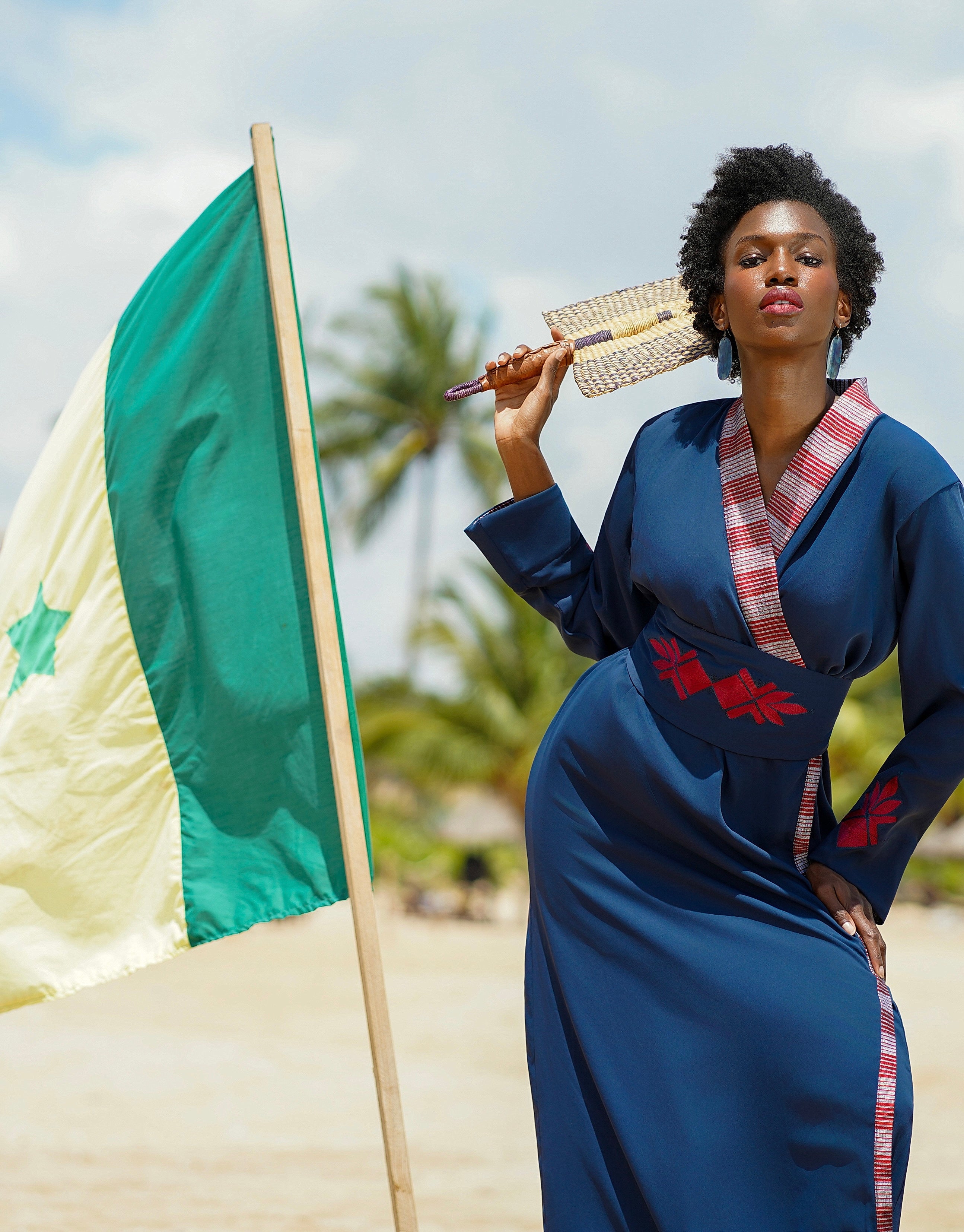 Woman in a blue dress with red artisan patterns and embroidered belt